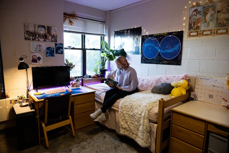 Caillyn Jeffery sits in her residence hall room, looking at a journal with a Studio 72 sticker attached to the front cover.