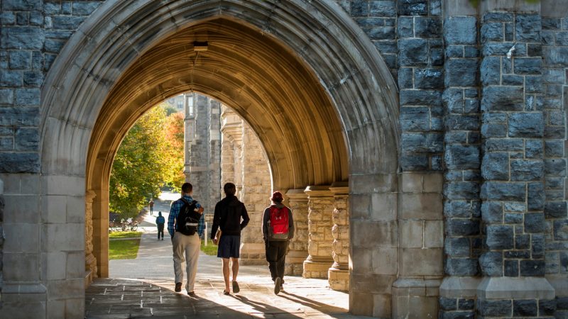 Students walk through an arch on Virginia Tech's campus in the fall during sunset. Photo by Logan Wallace for Virginia Tech.
