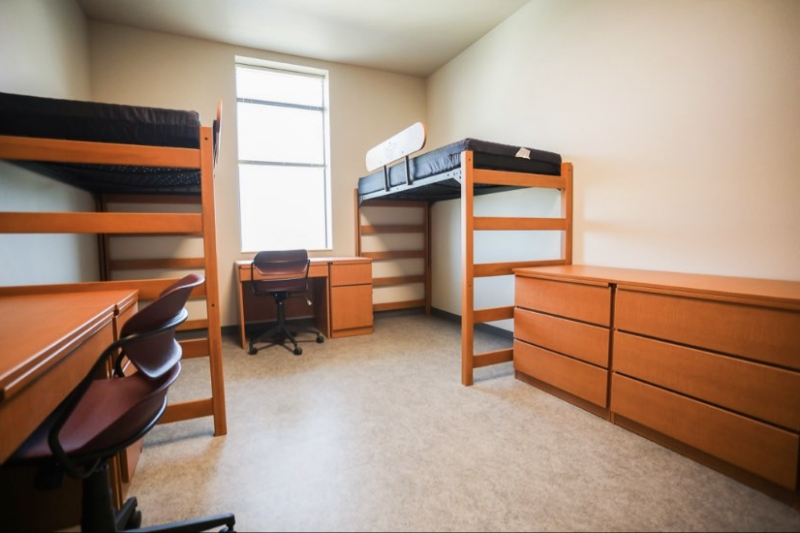 The inside of a traditional-style room in CID, with two lofted beds, desks, chairs, and dressers.