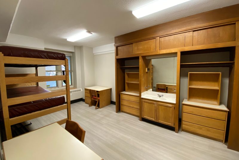Another view into a room in Eggleston Hall, focused on the built-in sink, mirror, clothing storage and along-ceiling cabinetry.