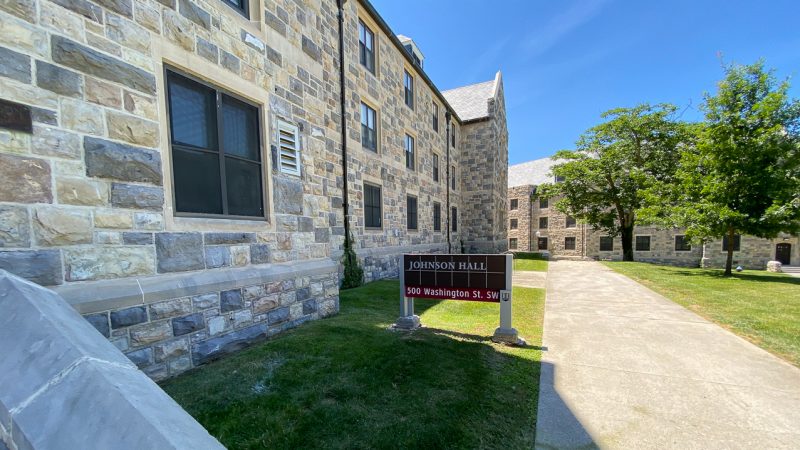 A view of the sign outside of Johnson Hall, with the side of the building on the left.