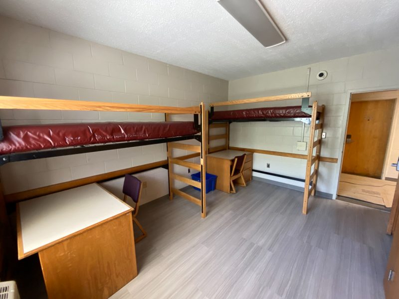 The inside of a traditional-style room in Johnson Hall, with two lofted beds, desks, and chairs.