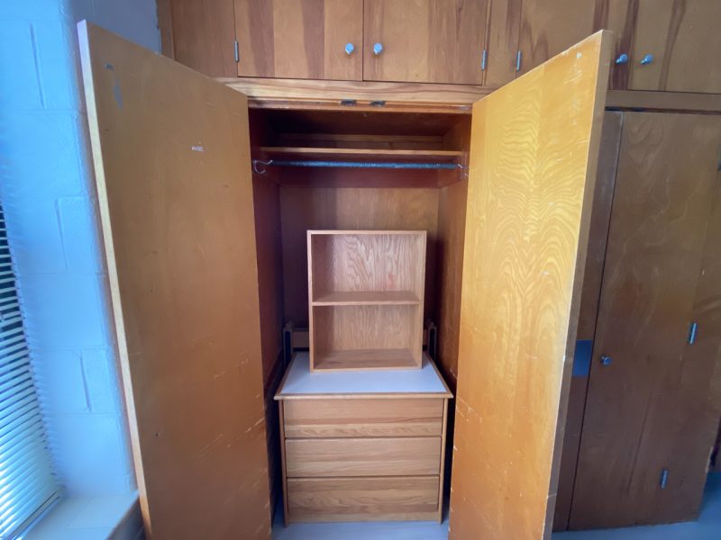 The doors of a built-in closet in Johnson Hall are open, revealing a dresser on the floor and a spot to hang clothes.