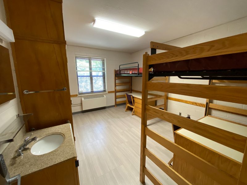The inside of a traditional-style room in Miles Hall, with two lofted beds, desks, chairs, a sink, and a mirror.