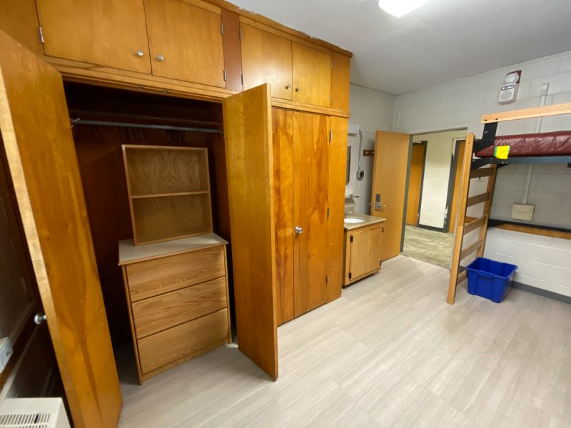 The doors of a built-in closet in Miles Hall are open, revealing a dresser on the floor and a spot to hang clothes.