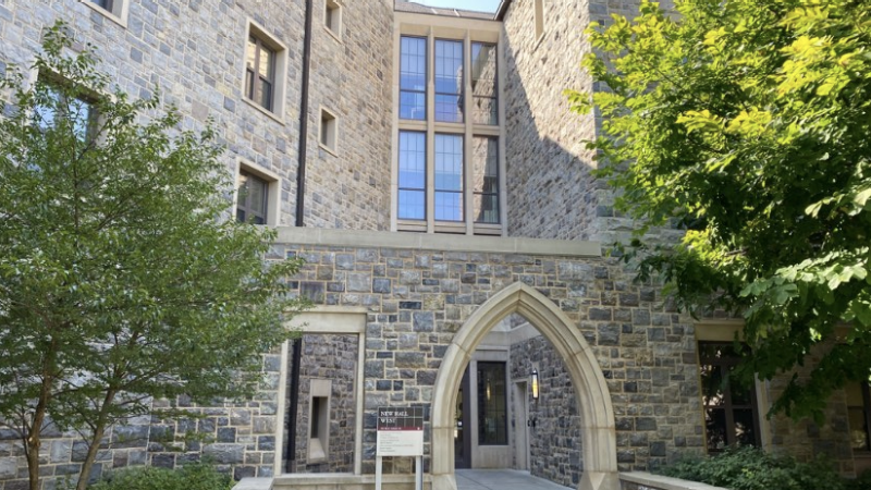 The main entrance of New Hall West. An archway overlooks the door, with greenery flanking the pathway up to the entrance.