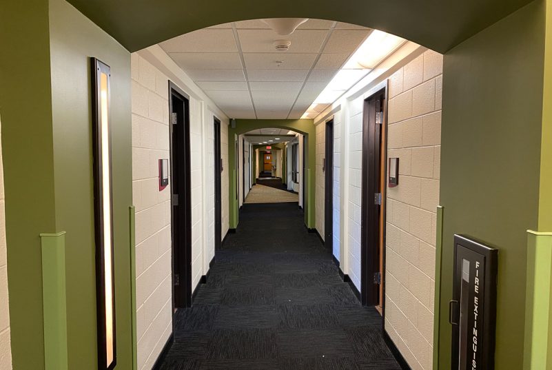 A view down one of Ambler Johnston's hallways, lined by green accents and doors to student rooms.