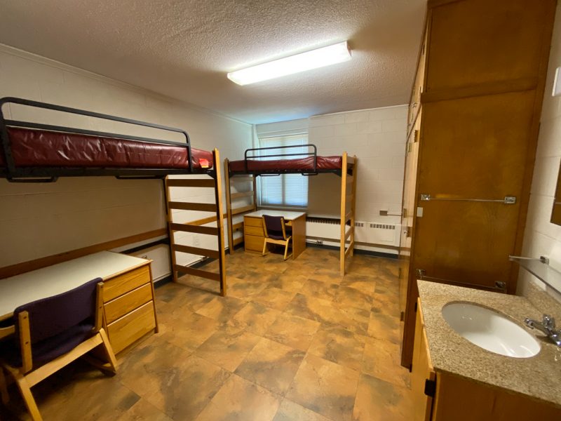The inside of a traditional-style room in Hoge Hall, with two lofted beds, desks, and chairs.