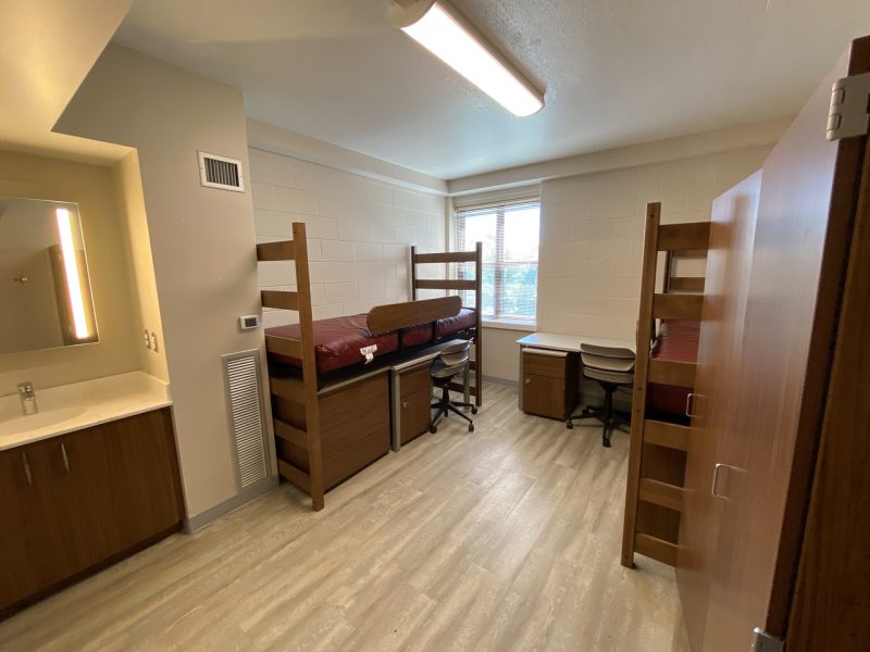 The inside of a traditional-style room in O'Shaughnessy Hall, with two lofted beds, desks, and chairs.