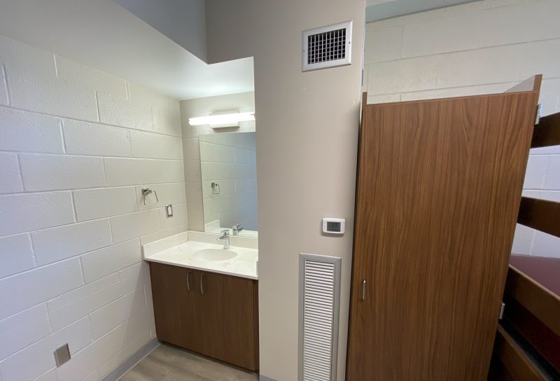 Another view into a room in O'Shaughnessy Hall, focused on the built-in sink, mirror, and clothing storage unit.