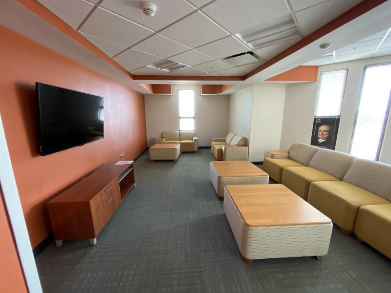 A common area in Pearson Hall East, with a wall-mounted TV and furniture spread out inside the room.
