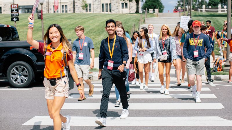 Students walk along a crosswalk on Virginia Tech's campus, lead by an orientation leader.