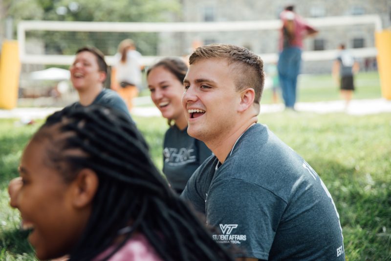 Students laughing and smiling sitting in a group on one of the quads on campus.